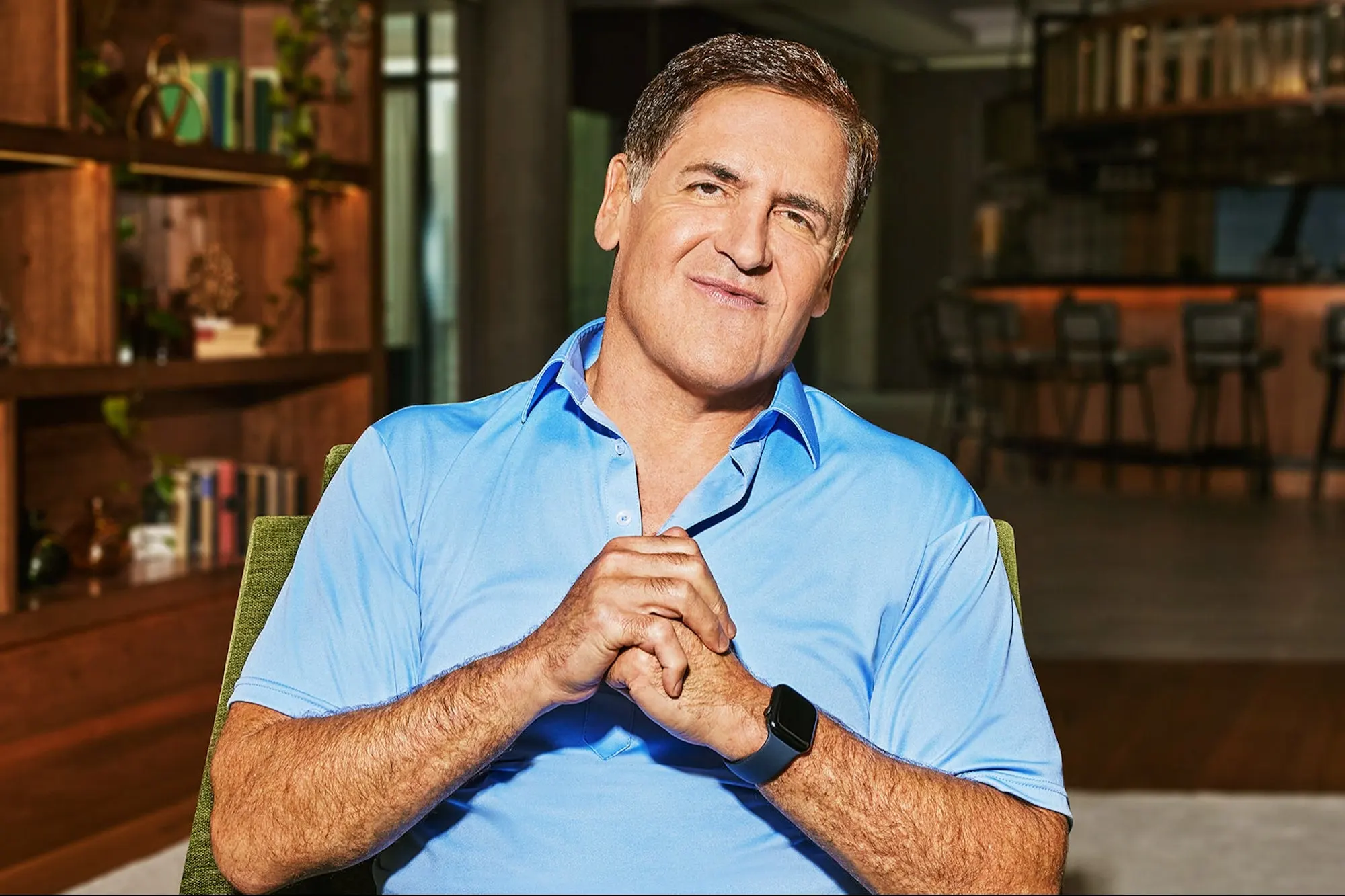 Portrait of Mark Cuban in a blue polo shirt seated in a lounge.