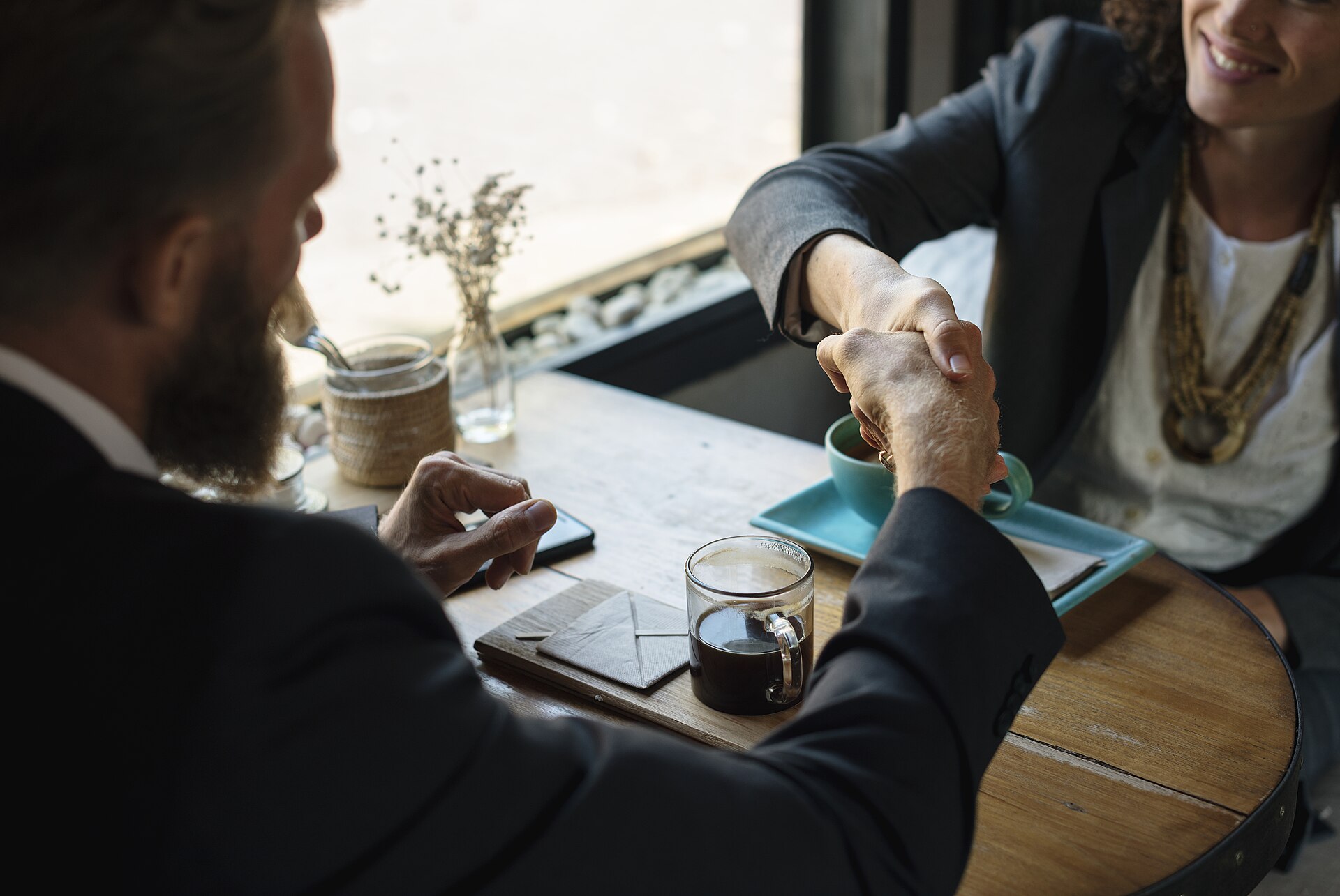Business partners shake hands across a table after reaching an agreement.